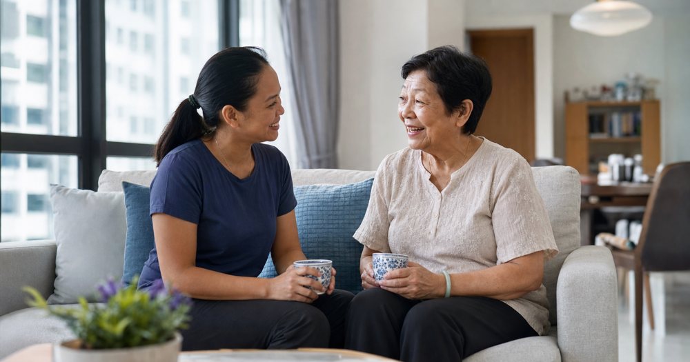 A helper sharing tea and conversation with an elderly woman